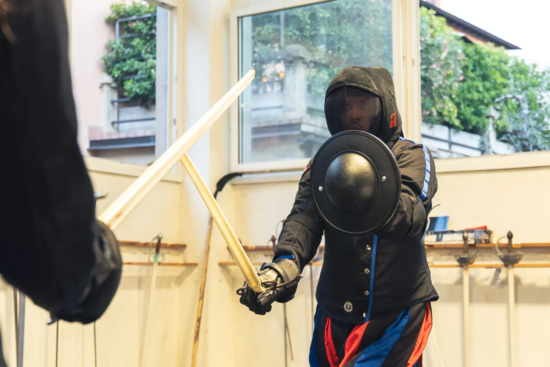 Allievo di Sword Academy con spada e brocchiero in guardia, il piccolo scudo bene in vista